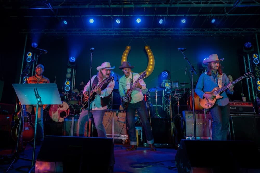 A band performing on an outdoor stage, lit against the evening.