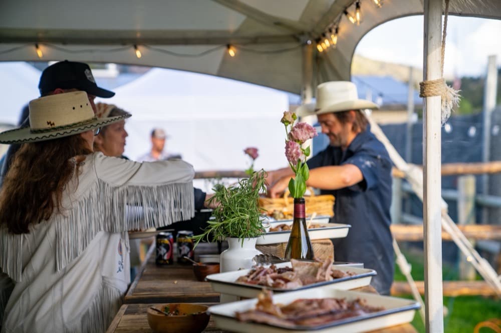 An open-sided tent set for serving food, with guests gathered under it.