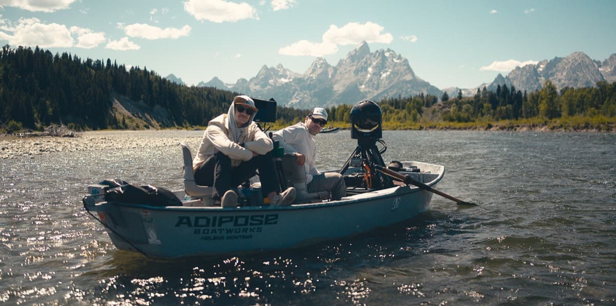 A film crew working from a drift boat beneath the Tetons