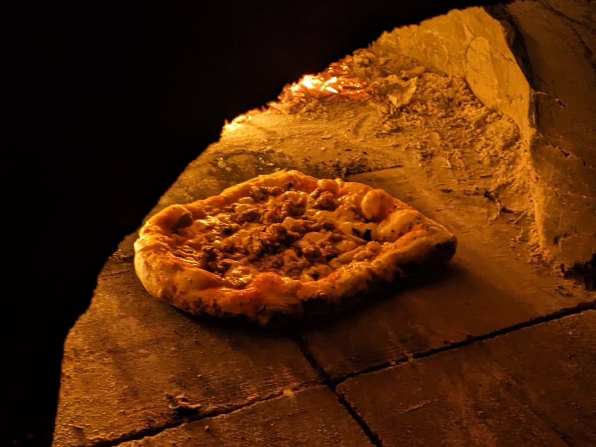 A pizza baking in the cob oven at a community dinner